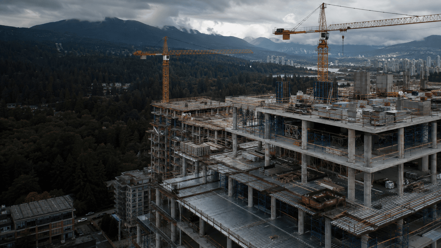 Illustrative aerial view of a concrete construction site and tower cranes with forested mountains